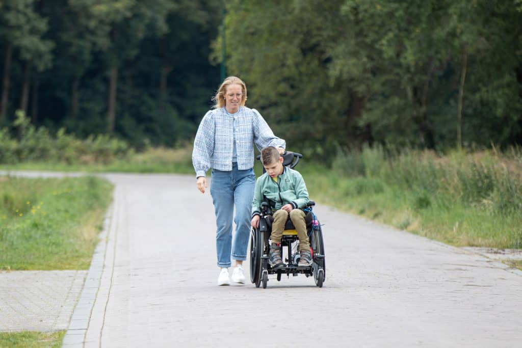 Mijke wandelt met Lars in zijn rolstoel